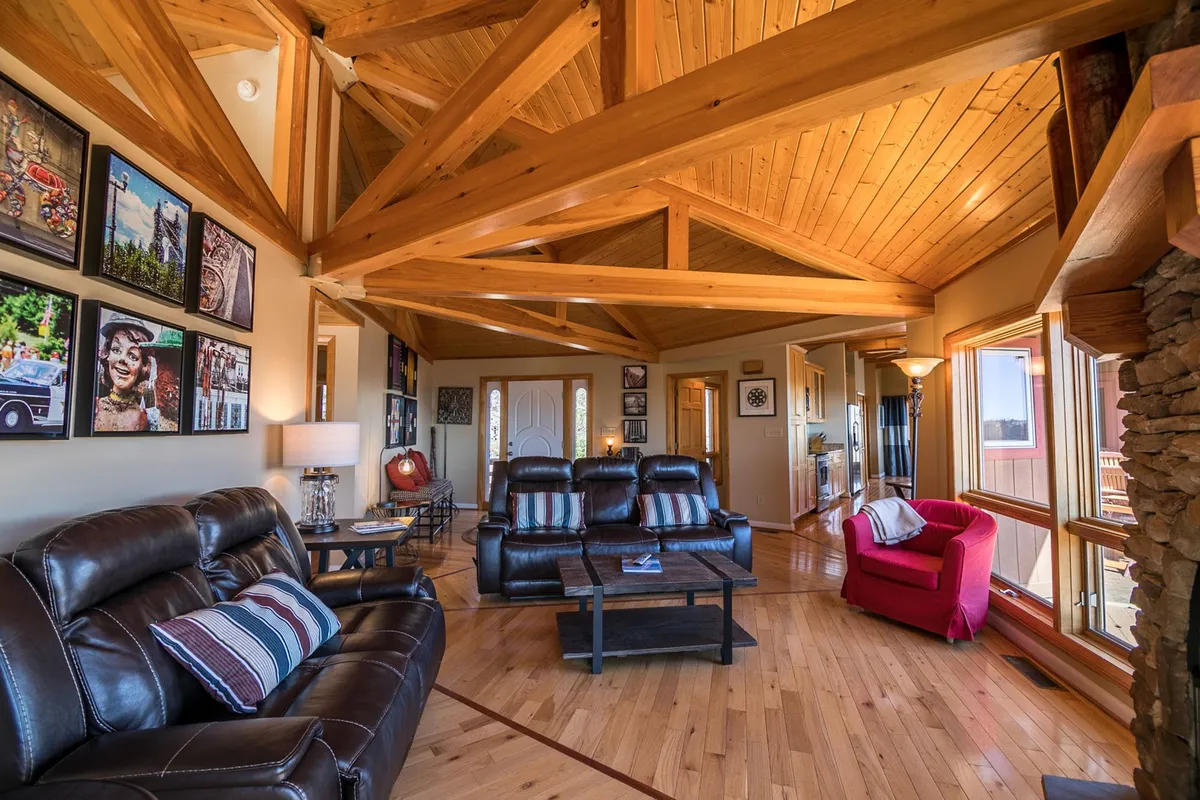 A stylish and comfortable living area with leather sofas, wooden beams, and wall art, arranged for relaxing or entertaining. The space feels warm and inviting, perfect for holiday gatherings or curling up with a book while snow falls outside.