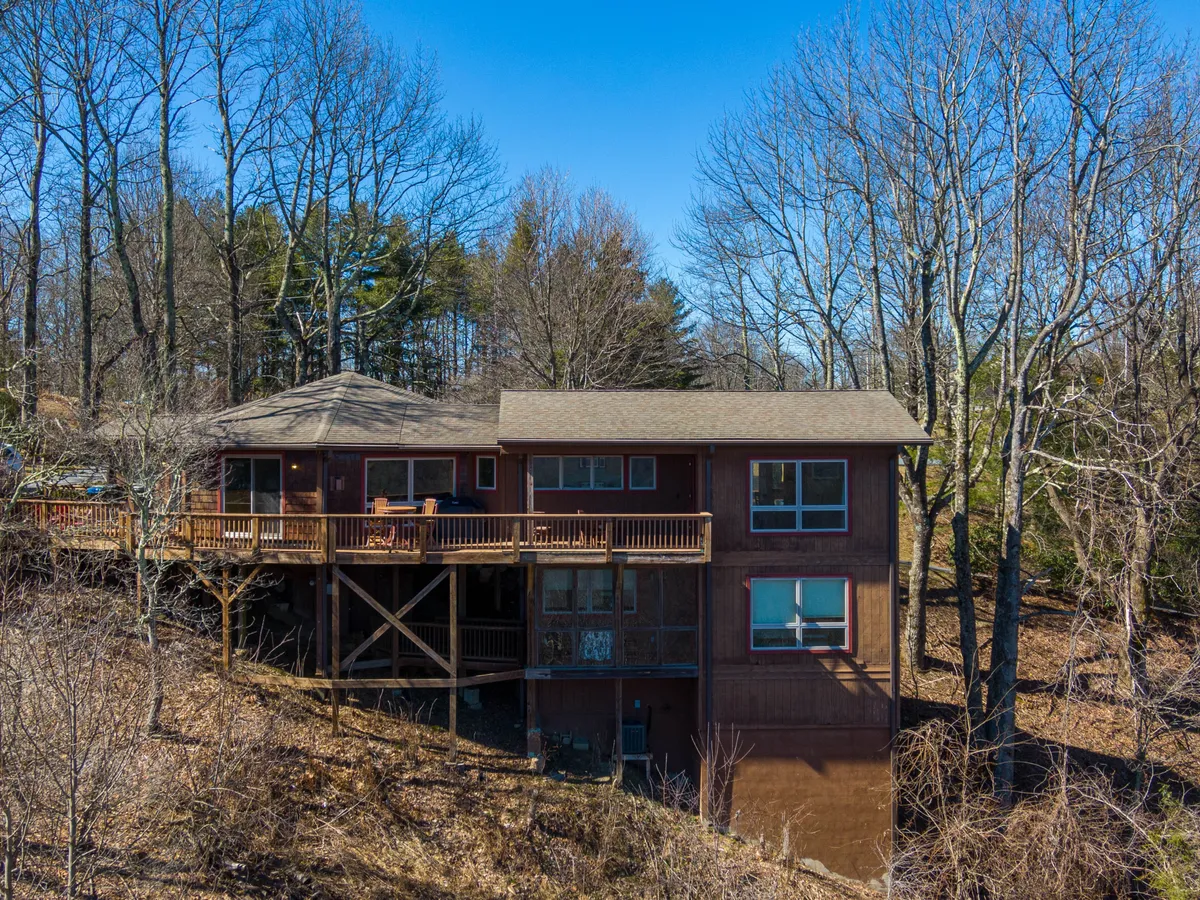 The inviting wooden deck overlooks natural scenery, framed by large windows that hint at the cozy interior. The deck provides a tranquil setting for gatherings, outdoor meals, or stargazing after a day of exploring.
