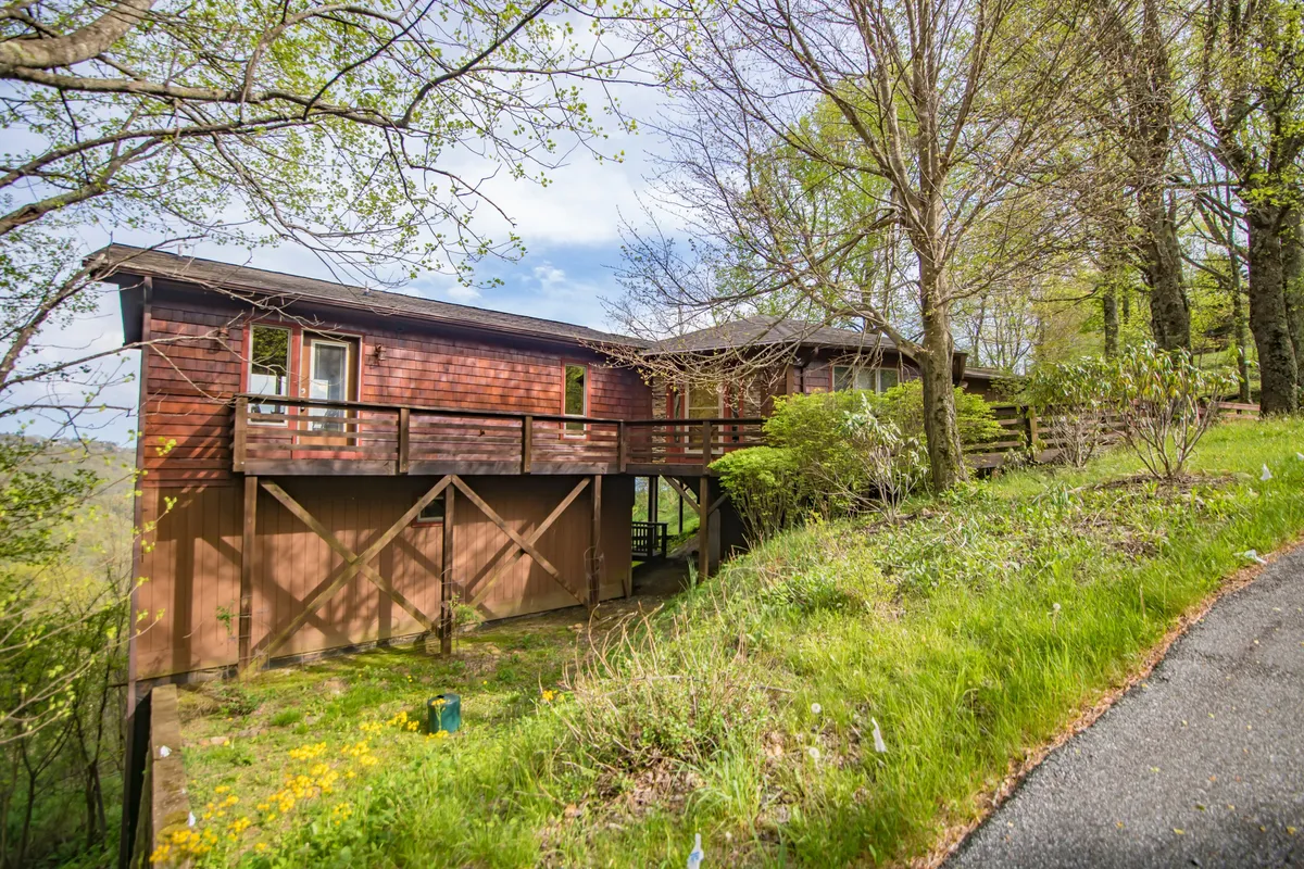 A wide exterior view of the home's charming wooden structure set among lush greenery, featuring a spacious balcony that offers a peaceful connection to nature. The setting is ideal for families to gather, relax, and enjoy the outdoors together.