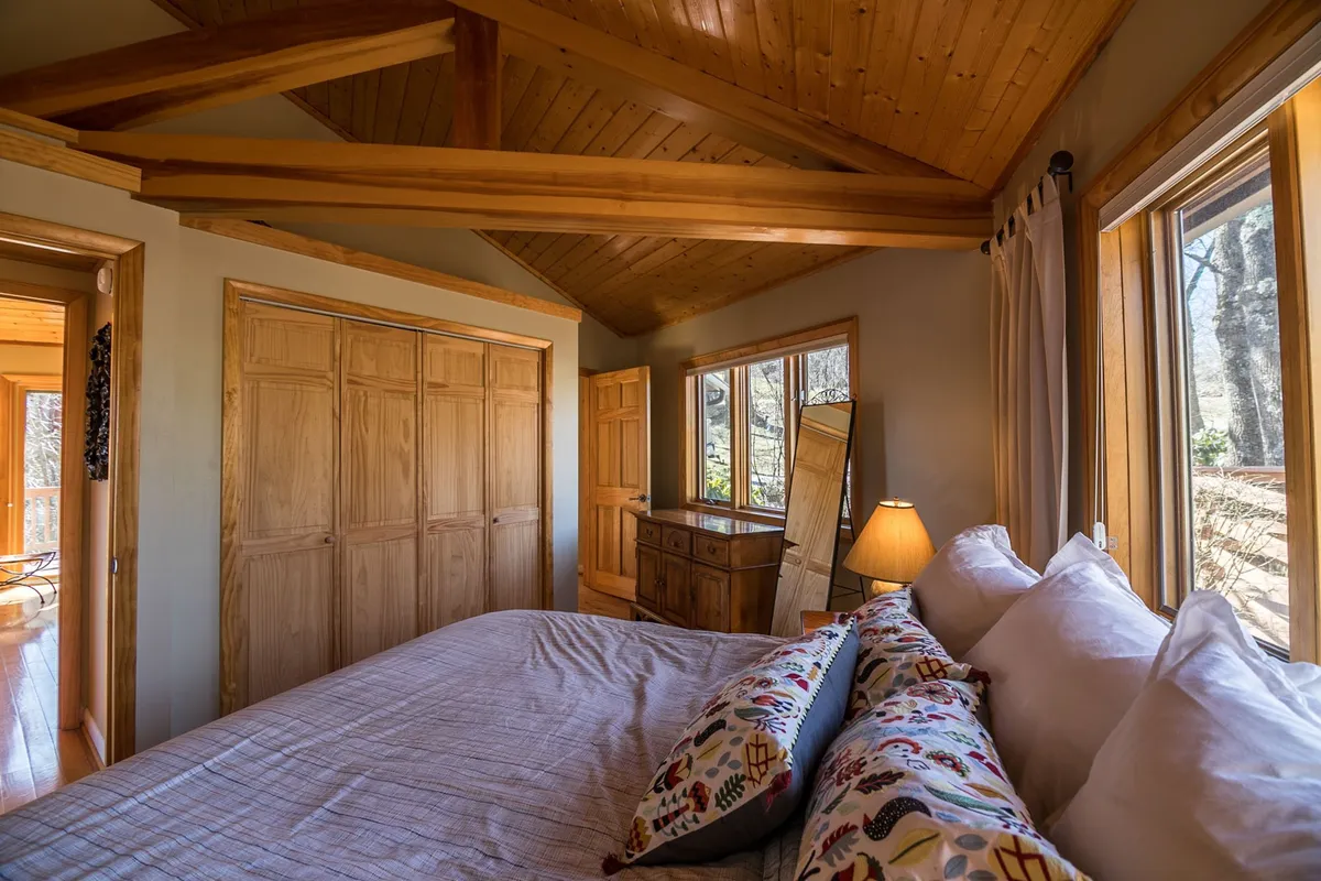 A cozy bedroom featuring a bed with decorative pillows and a wooden dresser stands out, with generous windows offering glimpses of the outdoors. The inviting setting suggests a restful retreat for both pet owners and their companions, emphasizing comfort after active days.