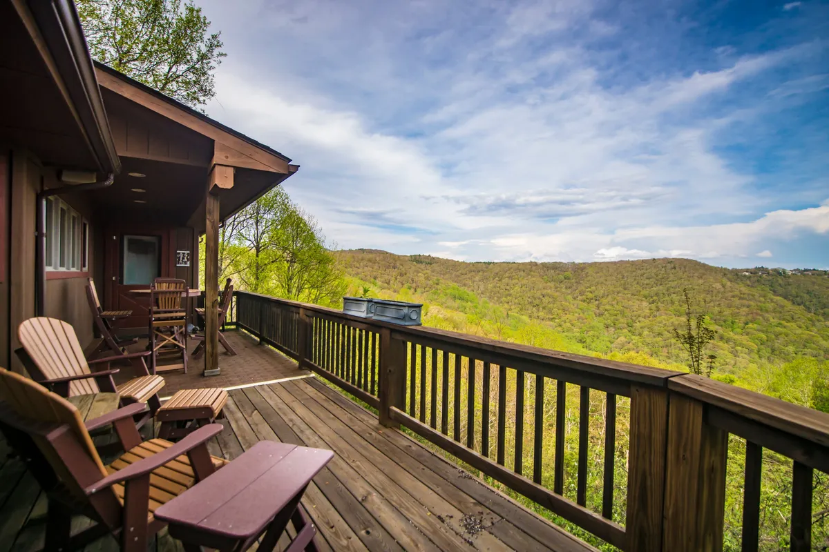 An exterior deck with Adirondack chairs overlooks a sweeping mountain view, inviting guests to relax, socialize, or simply soak up the natural beauty. The deck visually connects the interior living spaces to the outdoors.