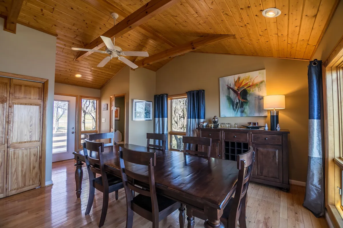 The image displays a cozy dining area featuring a wooden table set for a meal, surrounded by comfortable chairs. Artwork hangs on the wall, and a stylish sideboard with a lamp adds warmth and character to the space, suggesting a place for socializing after outdoor activities.